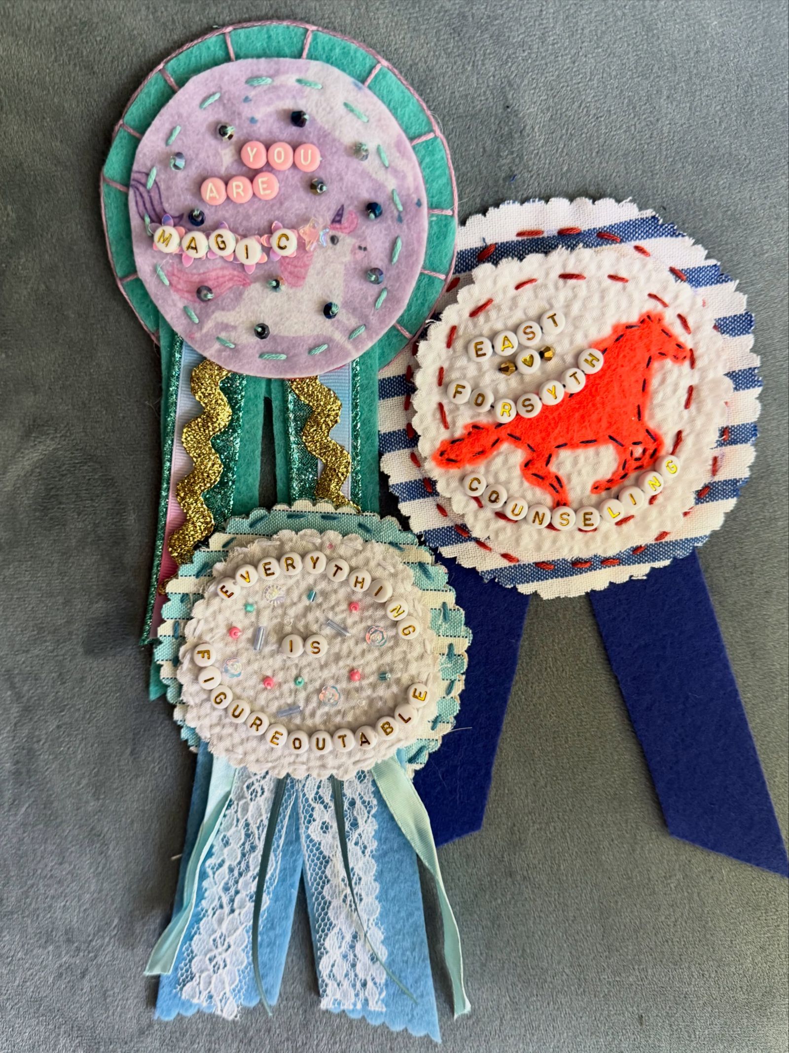 A cluster of handmade felt prize ribbons reading you are magic and everything is figureoutable